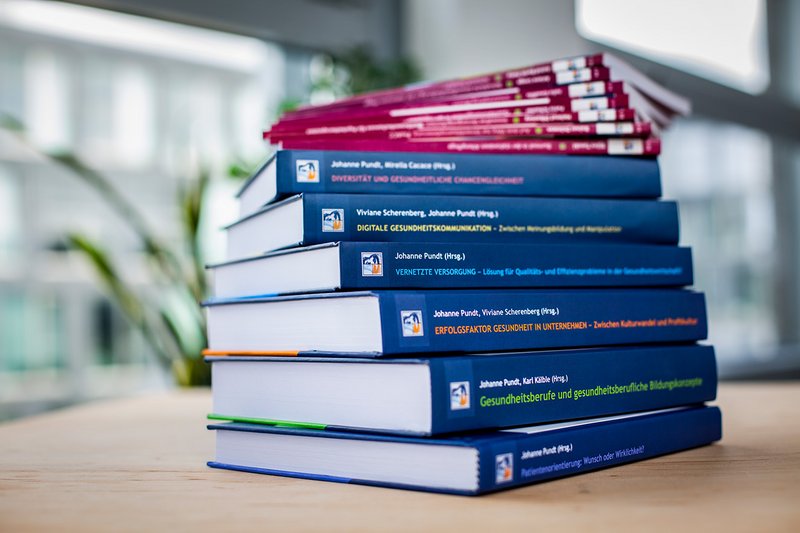 Bücherstapel verschiedener Publikationen aus dem Verlag APOLLON University Press.