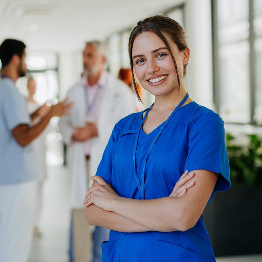 Pflegerin im Vordergrund mit Pfleger und Arzt im Hintergrund