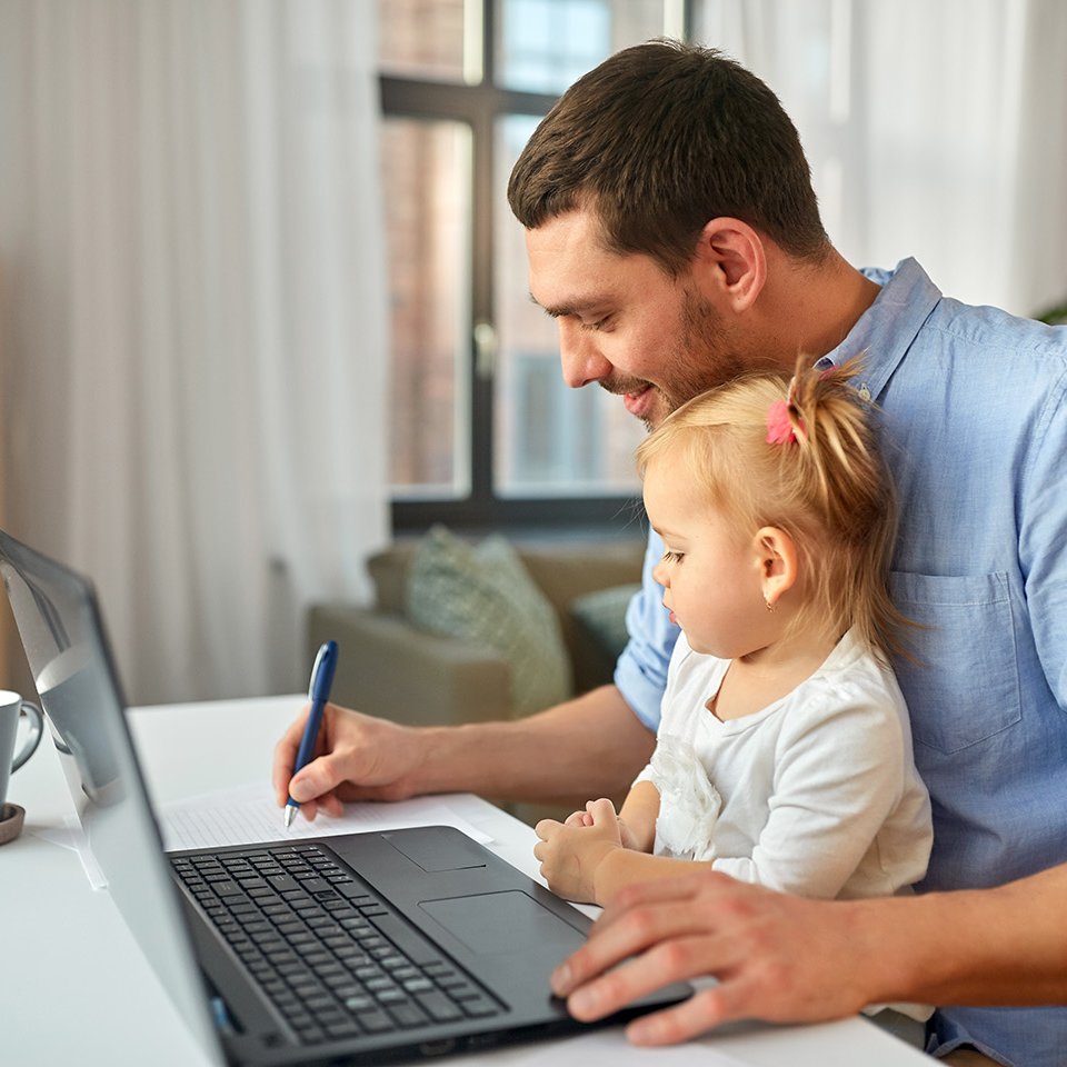 Mann sitzt mit Baby an Laptop